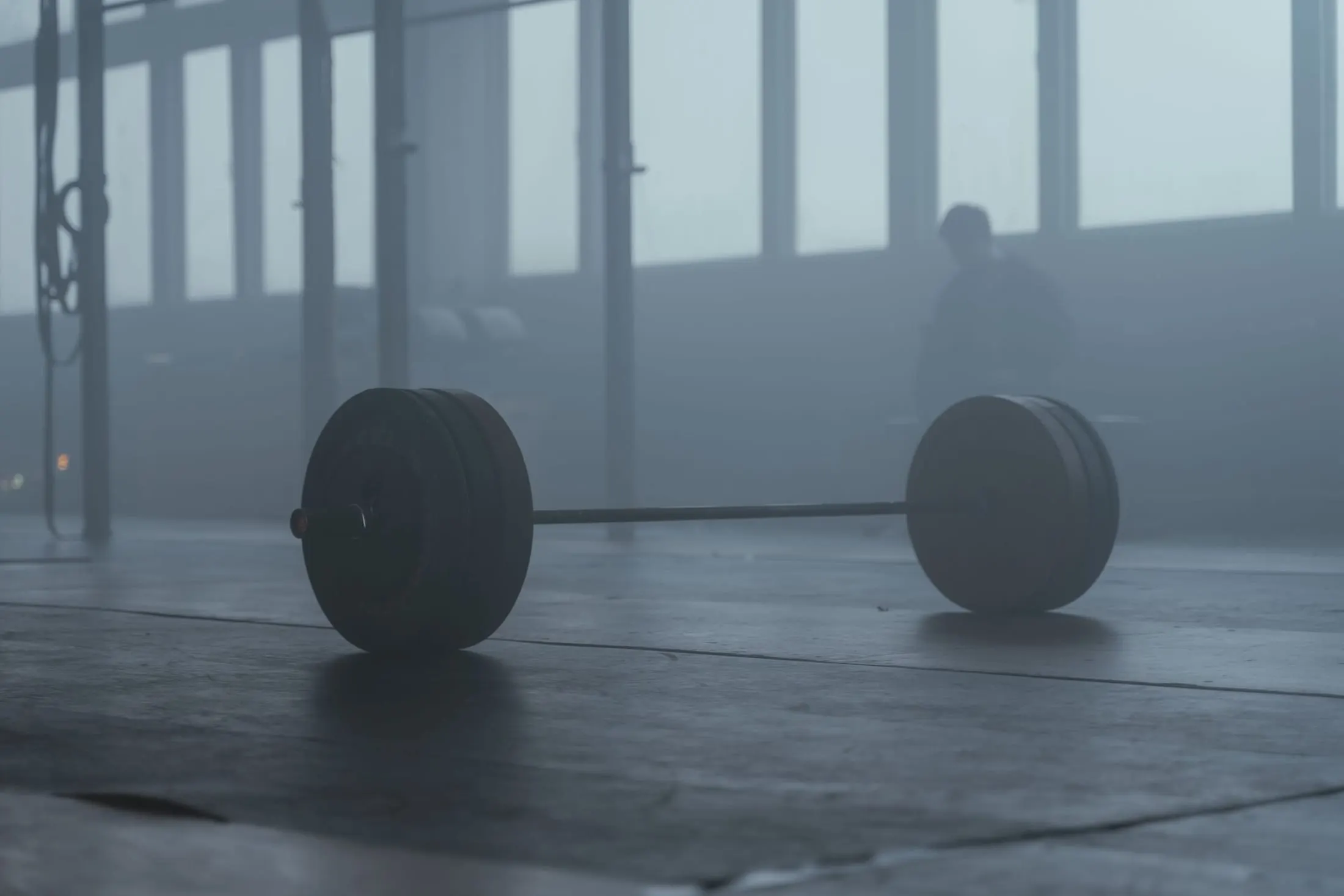 Barra olímpica cargada en el piso del gimnasio