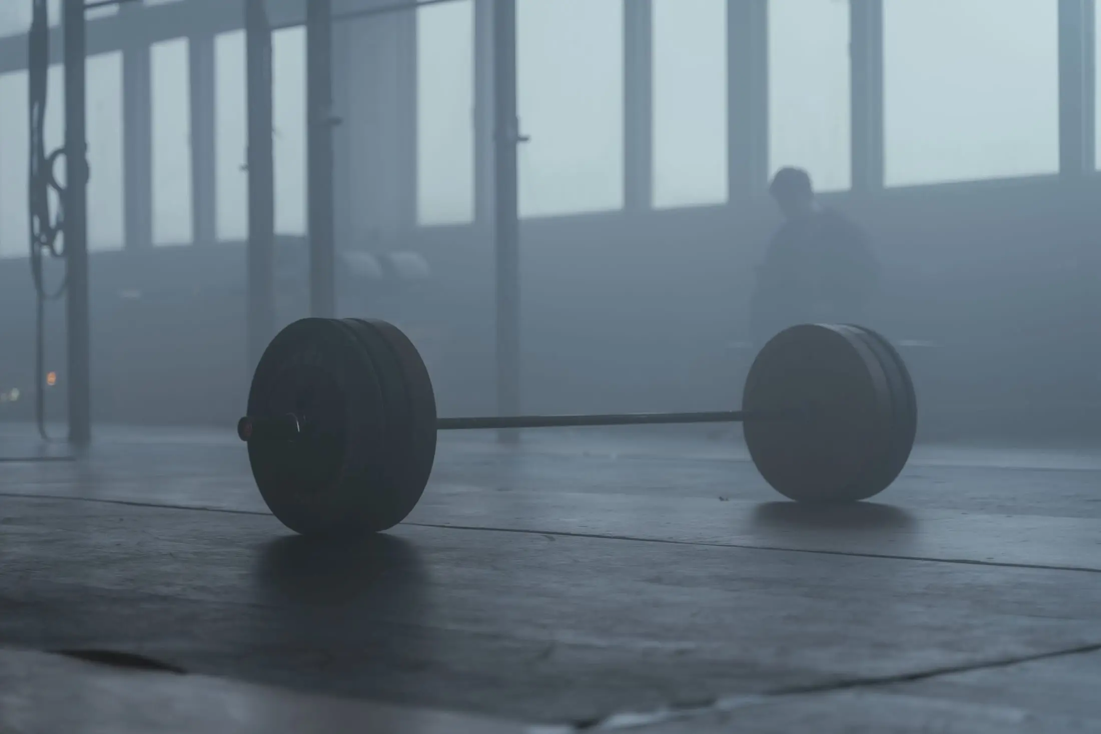 Barra olímpica cargada en el piso del gimnasio